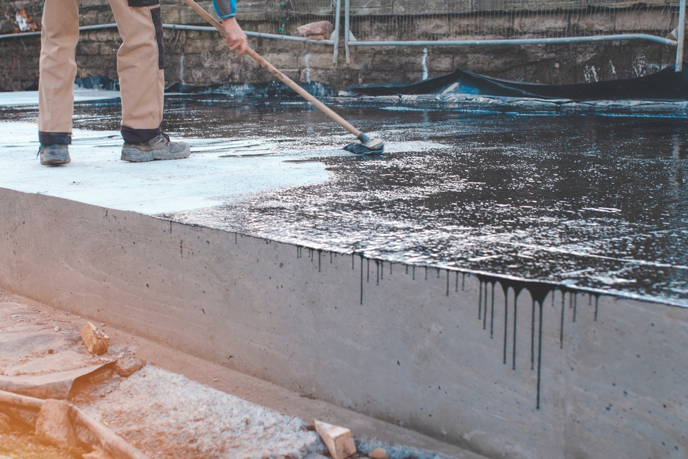 Worker,Applying,Black,Waterproofing,Material,To,Concrete,Foundation